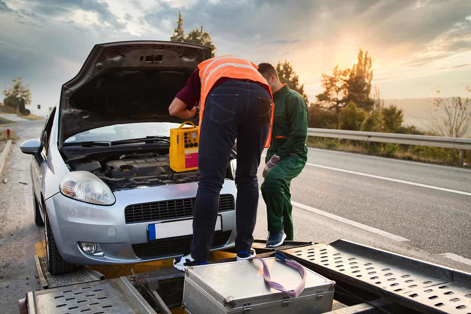 Technician providing roadside assistance and car battery jump start